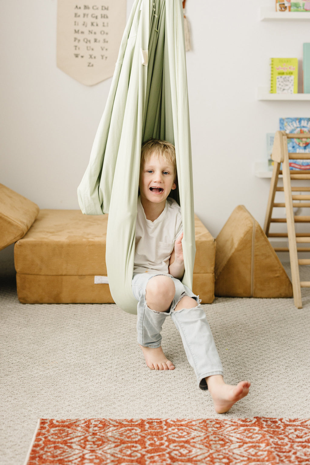 Child sitting and playing in Desert Sage sensory swing in playroom
