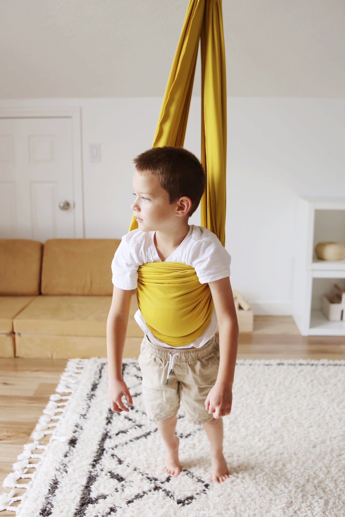 Child standing inside Retro Pineapple sensory swing in playroom