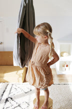 Child standing beside a Stone double-layer sensory swing hanging in an indoor playroom.