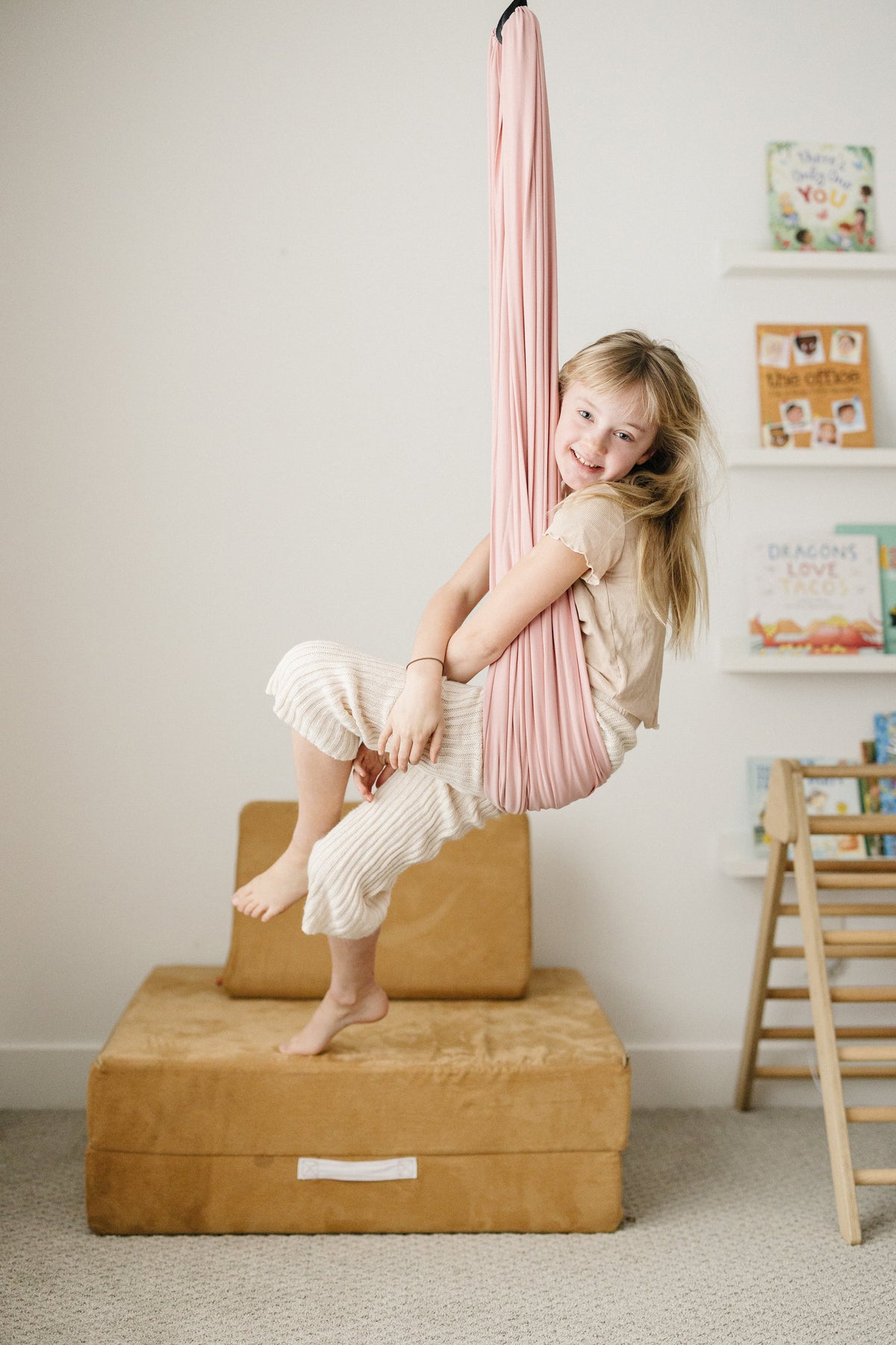Child relaxing in Vintage Rose sensory swing in indoor playroom