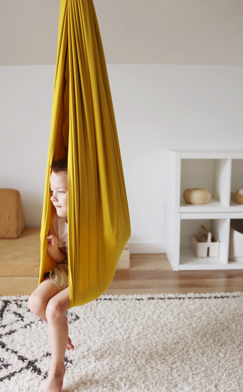 Child relaxing inside Retro Pineapple sensory swing in a playroom