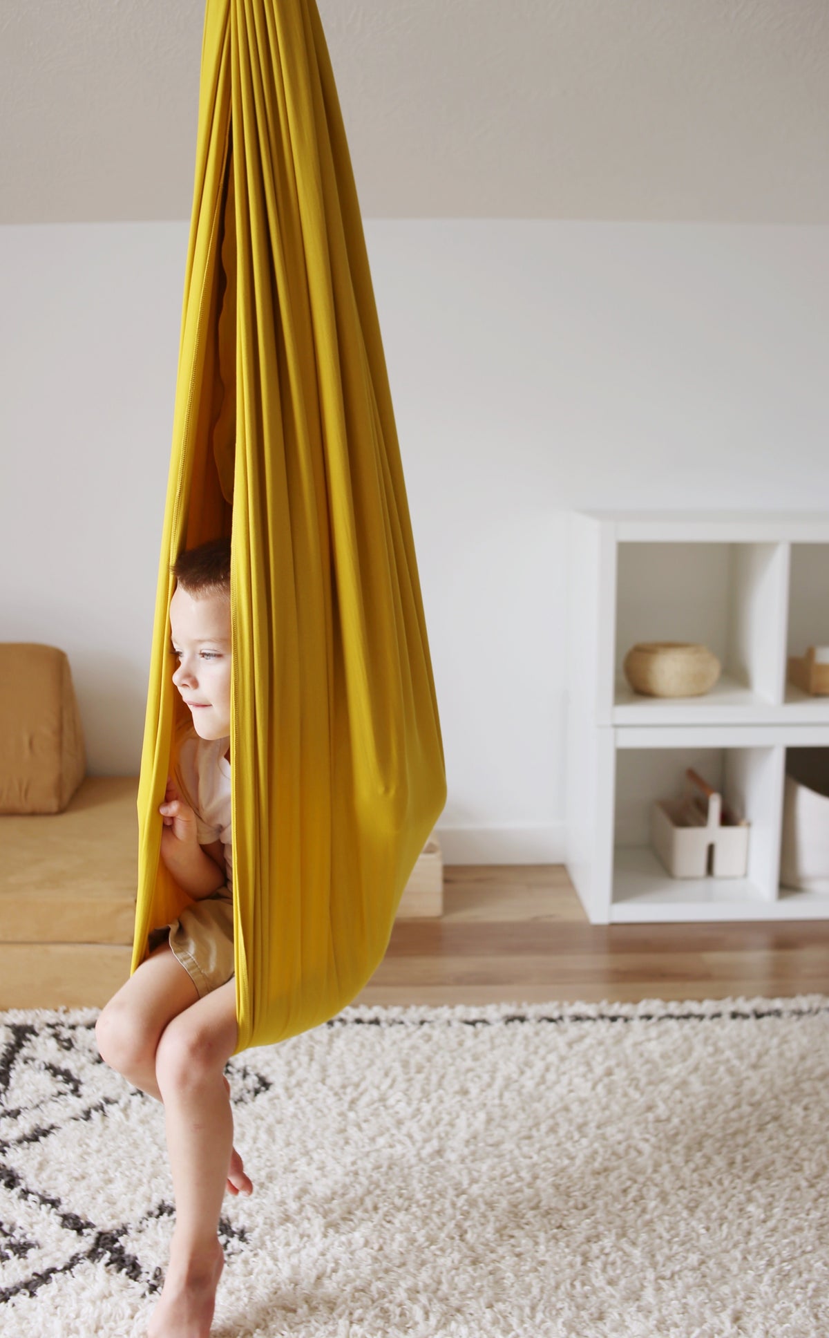 Child relaxing inside Retro Pineapple sensory swing in a playroom