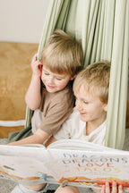 Two children reading together in Desert Sage sensory swing