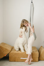 Child relaxing in a Stone double-layer sensory swing with a dog beside her in a playroom.