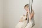 Child relaxing in a Stone double-layer sensory swing while interacting with a dog.