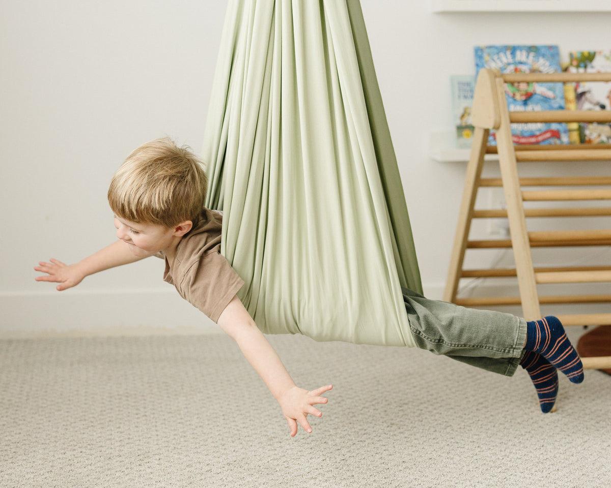 Child using Desert Sage sensory swing for active indoor play and movement