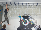 Cargo net tunnel and ceiling monkey bars in a kids' playroom