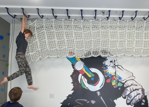 Cargo net tunnel and ceiling monkey bars in a kids' playroom