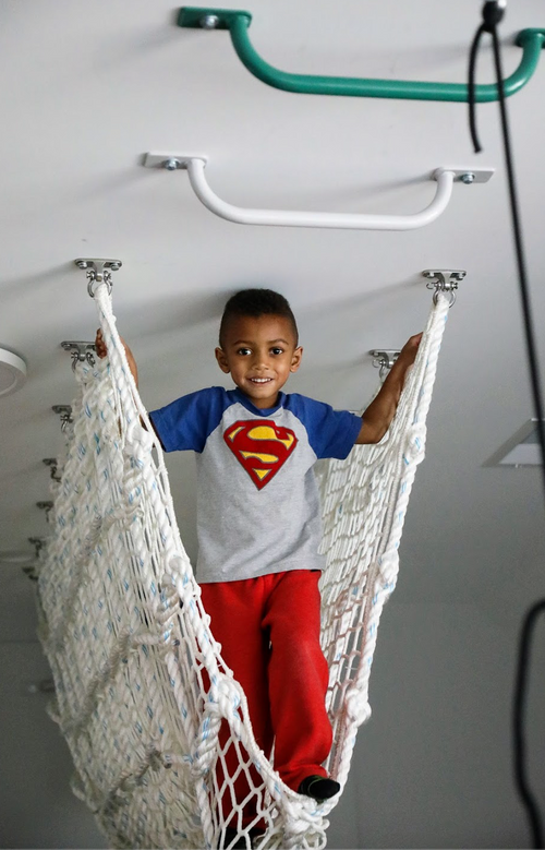 Young child standing inside a suspended net tunnel in a home playroom