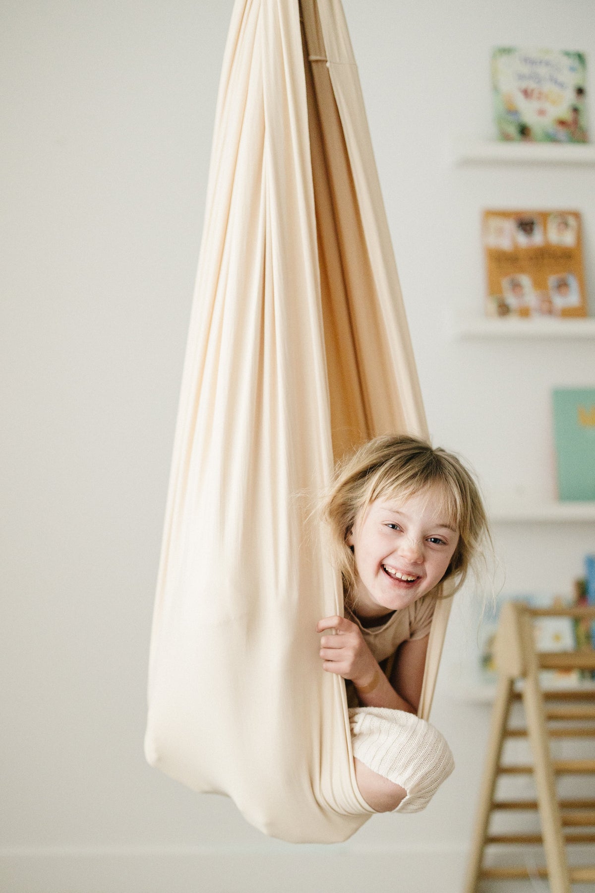 Child smiling while sitting in Oat double-layer sensory swing