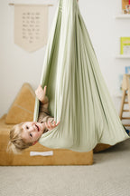 Child hanging upside down in Desert Sage double-layer sensory swing