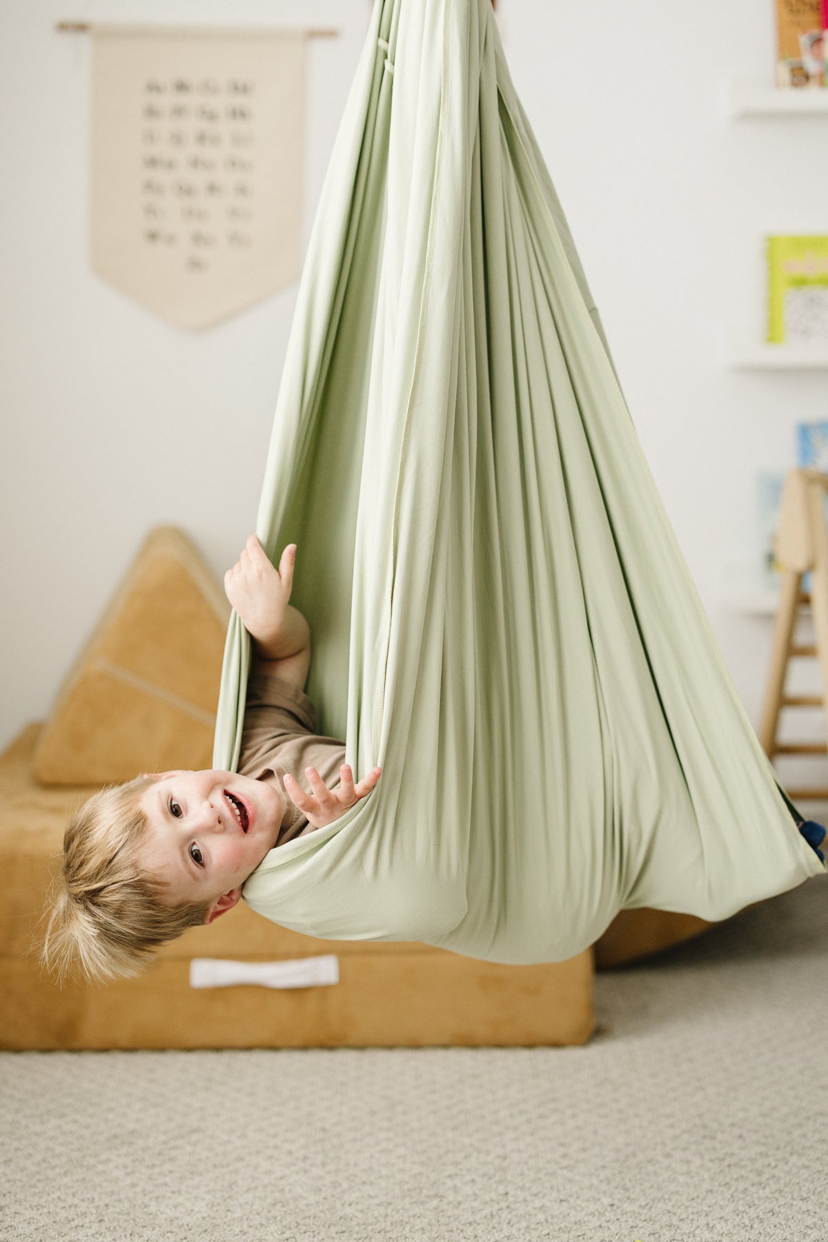 Child hanging upside down in Desert Sage double-layer sensory swing