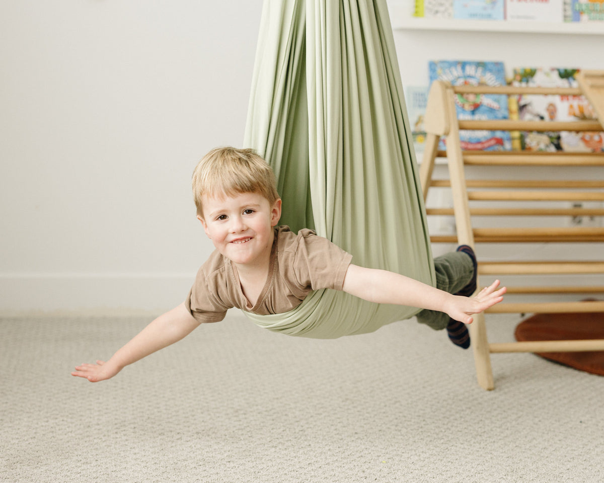Child playing and swinging in Desert Sage double-layer sensory swing
