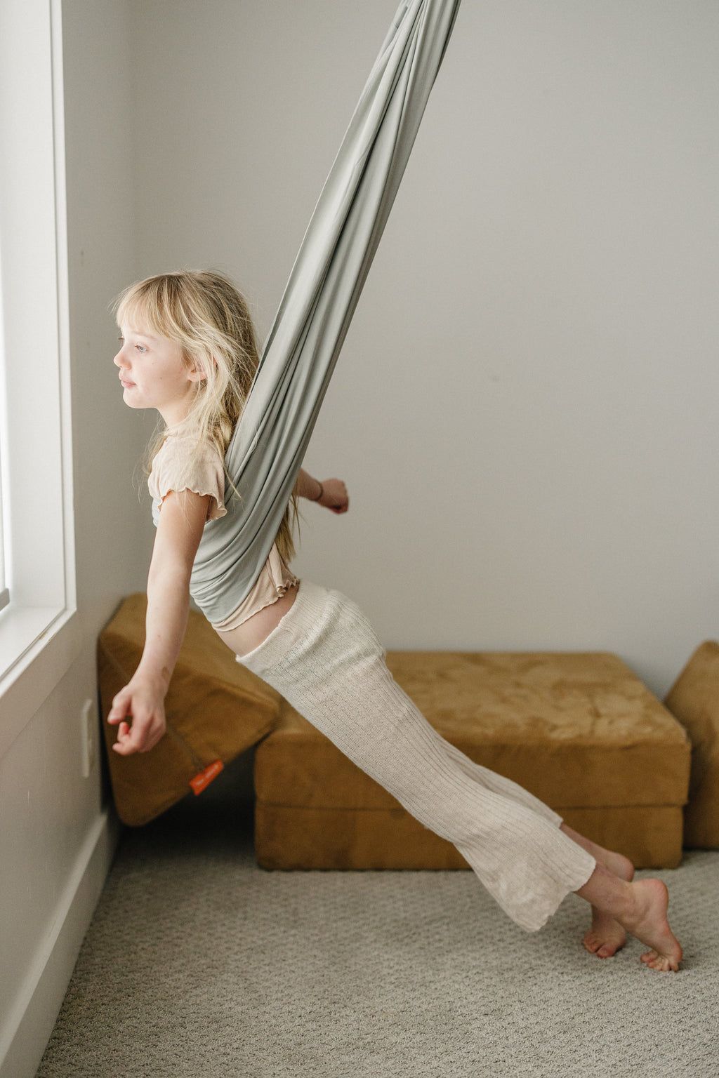 Child swinging in a Stone double-layer sensory swing in an indoor playroom.