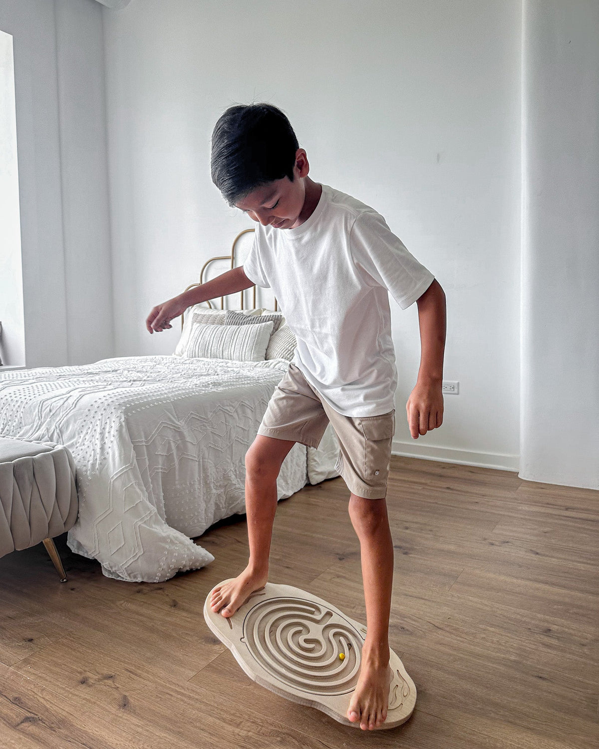Child standing on a wobble board with maze on a bedroom floor