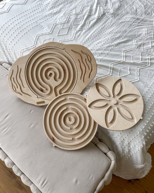Two kids balance boards with marble maze tops resting on a bed