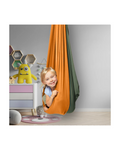 child smiling in reversible orange and green indoor sensory swing in playroom