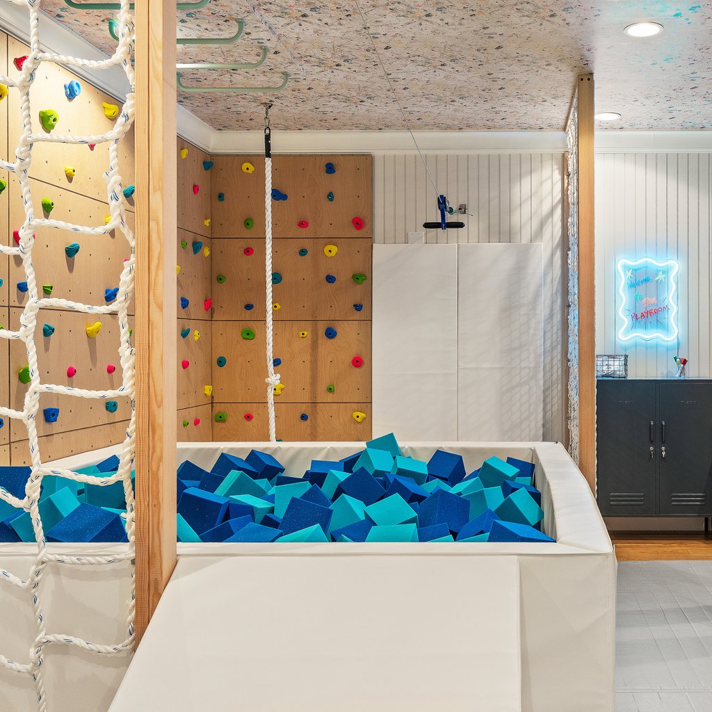 Custom indoor playroom with climbing wall, cargo net and foam pit filled withal and blue foam cubes