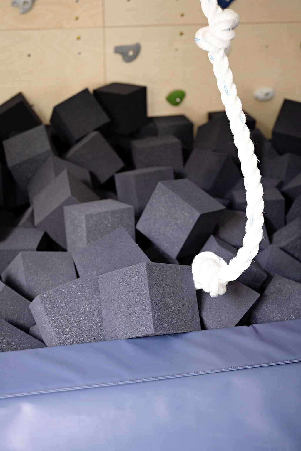 Charcoal foam cubes filling a foam pit under a climbing rope