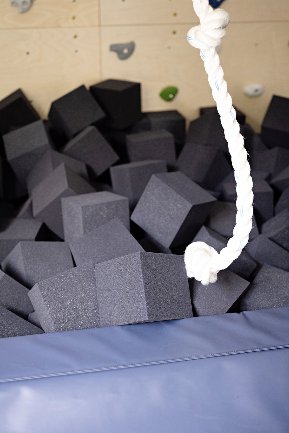 Charcoal foam cubes filling a foam pit under a climbing rope