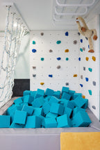 Children's play area with blue foam cubes, climbing wall, and monkey plush toy.