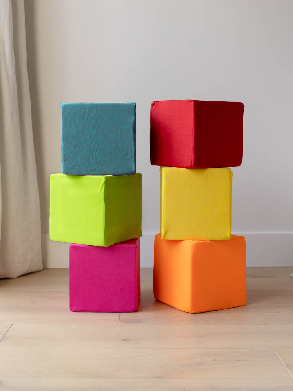 Two stacked towers of foam cubes in colorful fabric covers: turquoise, red, lime, yellow, pink and orange